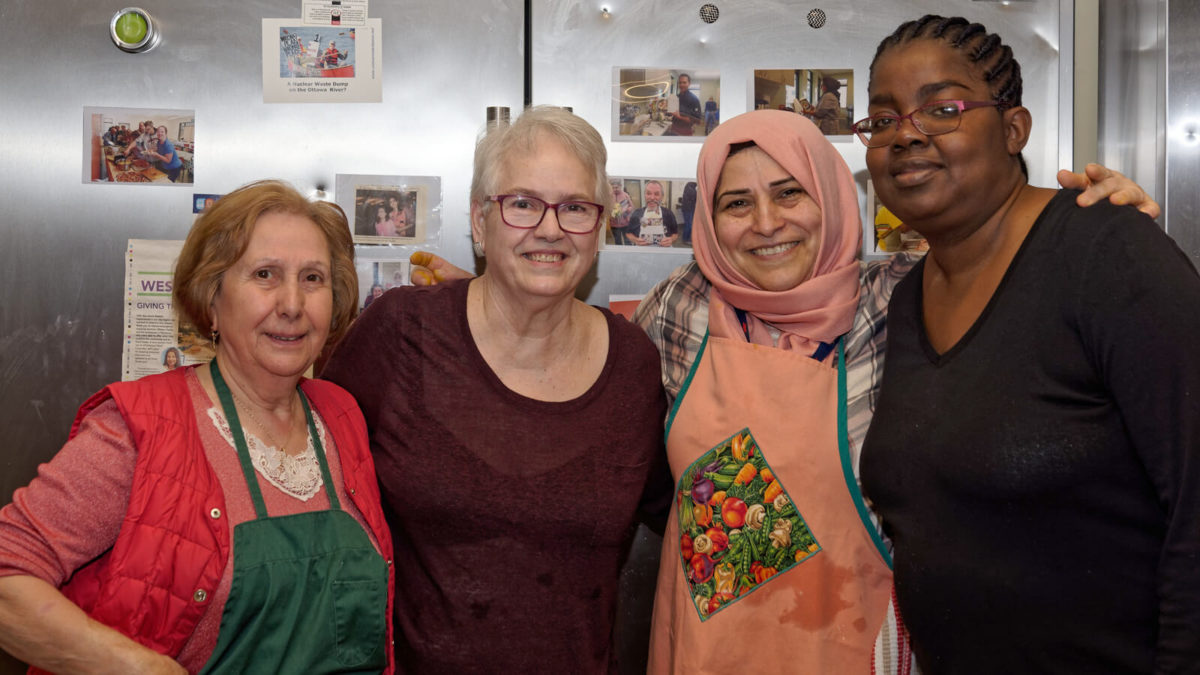 Four women in aprons in a kitchen