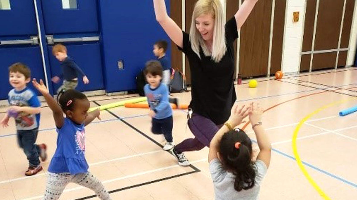 Teacher showing young children how to lunge and raise their arms